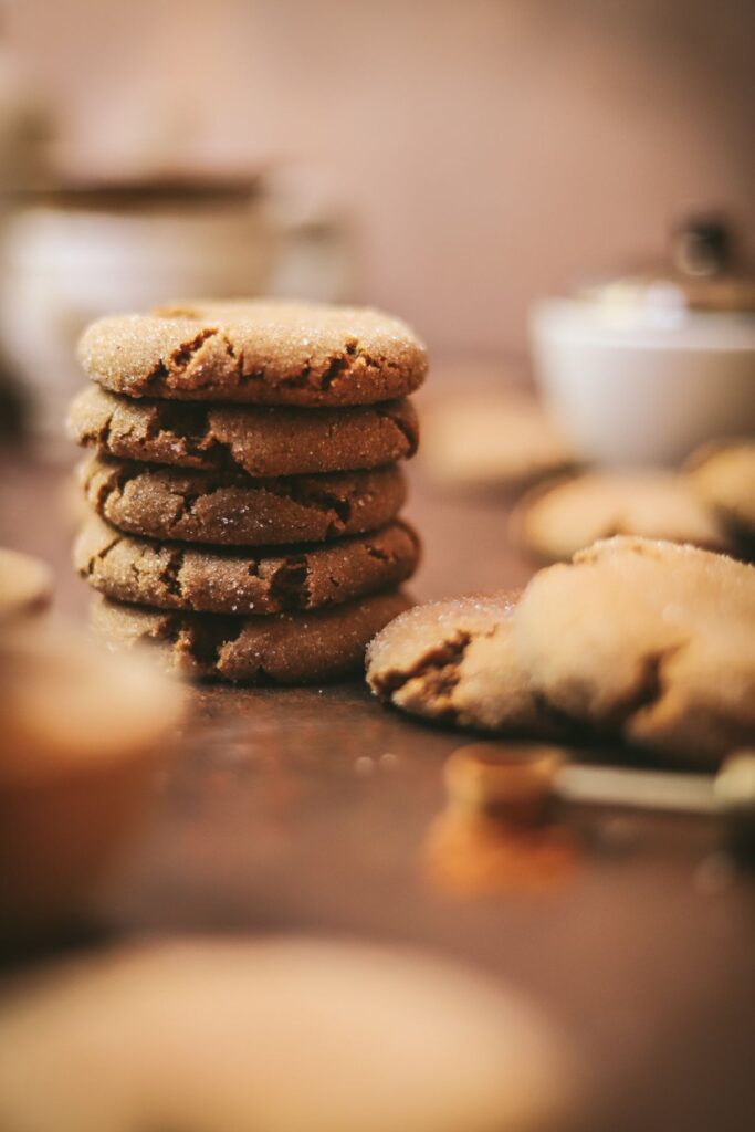 A stack of molasses cookies with coffee in the background. 