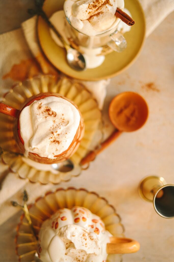 A trio of pumpkin spice lattes with bourbon, topped with whipped cream.