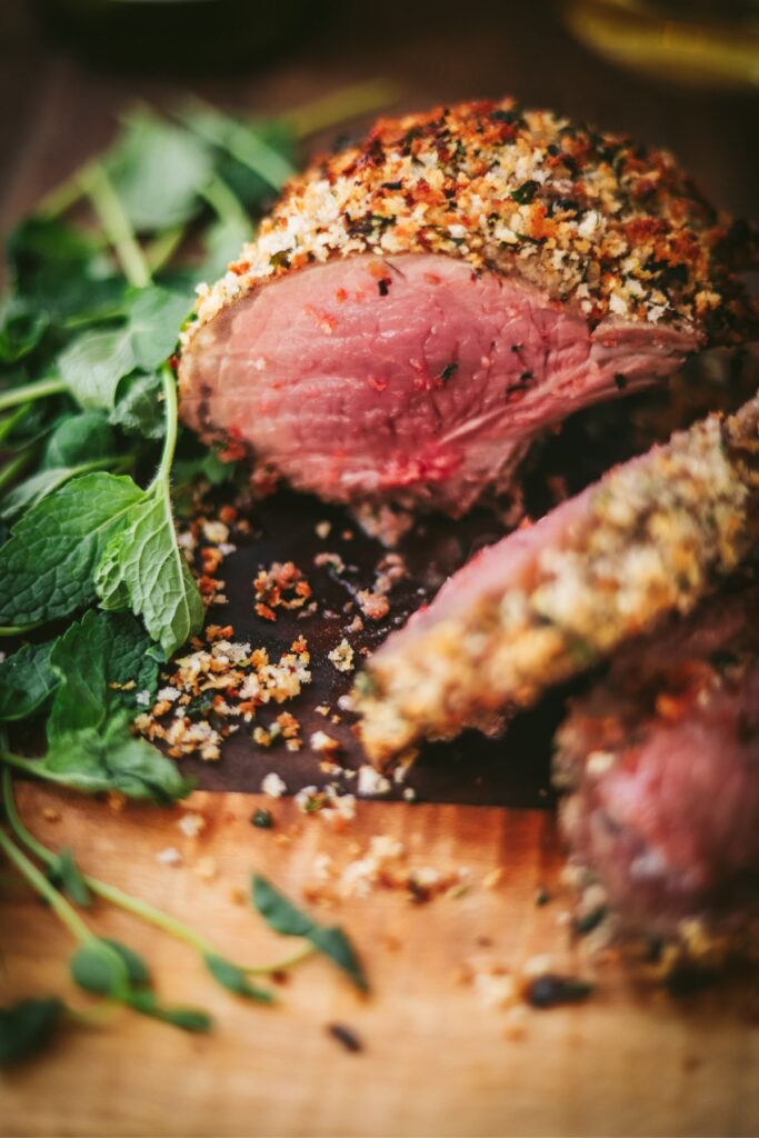 Herb-crusted rack of lamb on a wooden cutting board. 