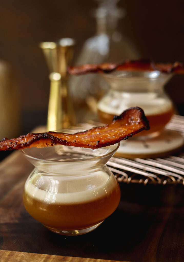 Two glasses of maple whisky sours with candied bacon