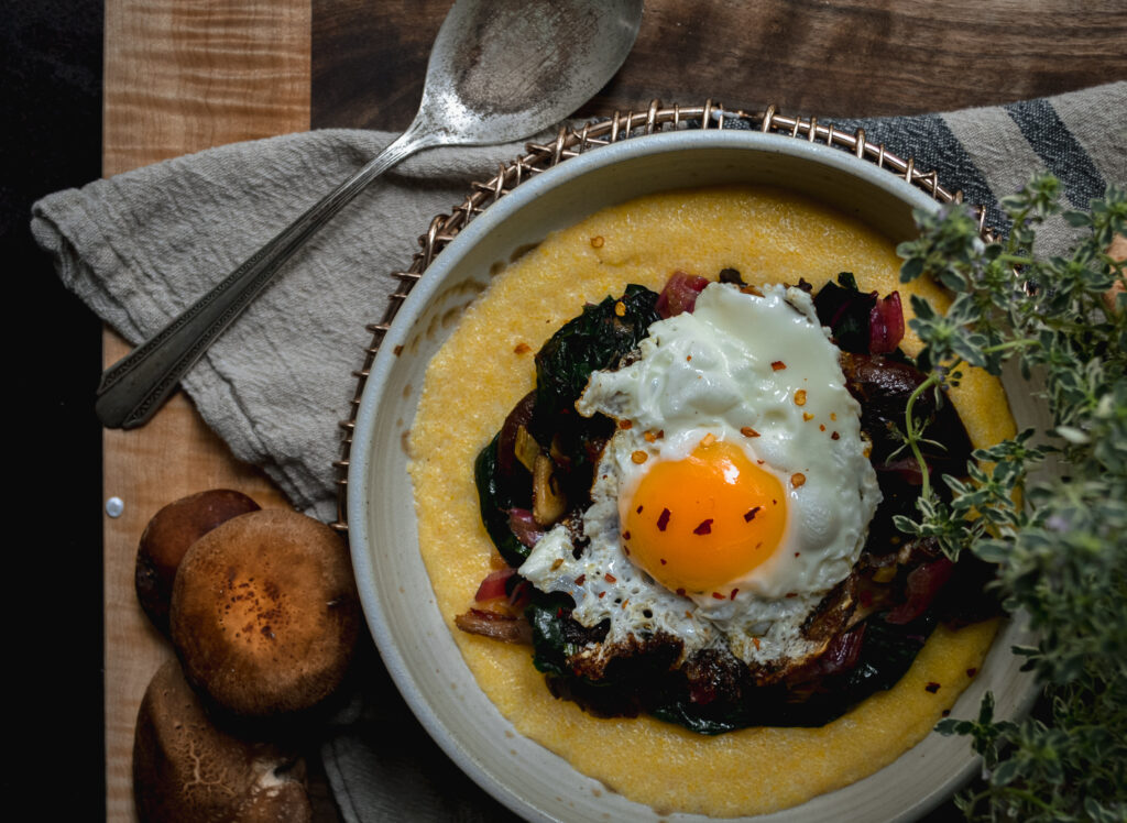 A fried egg on a bed of swiss chard and polenta