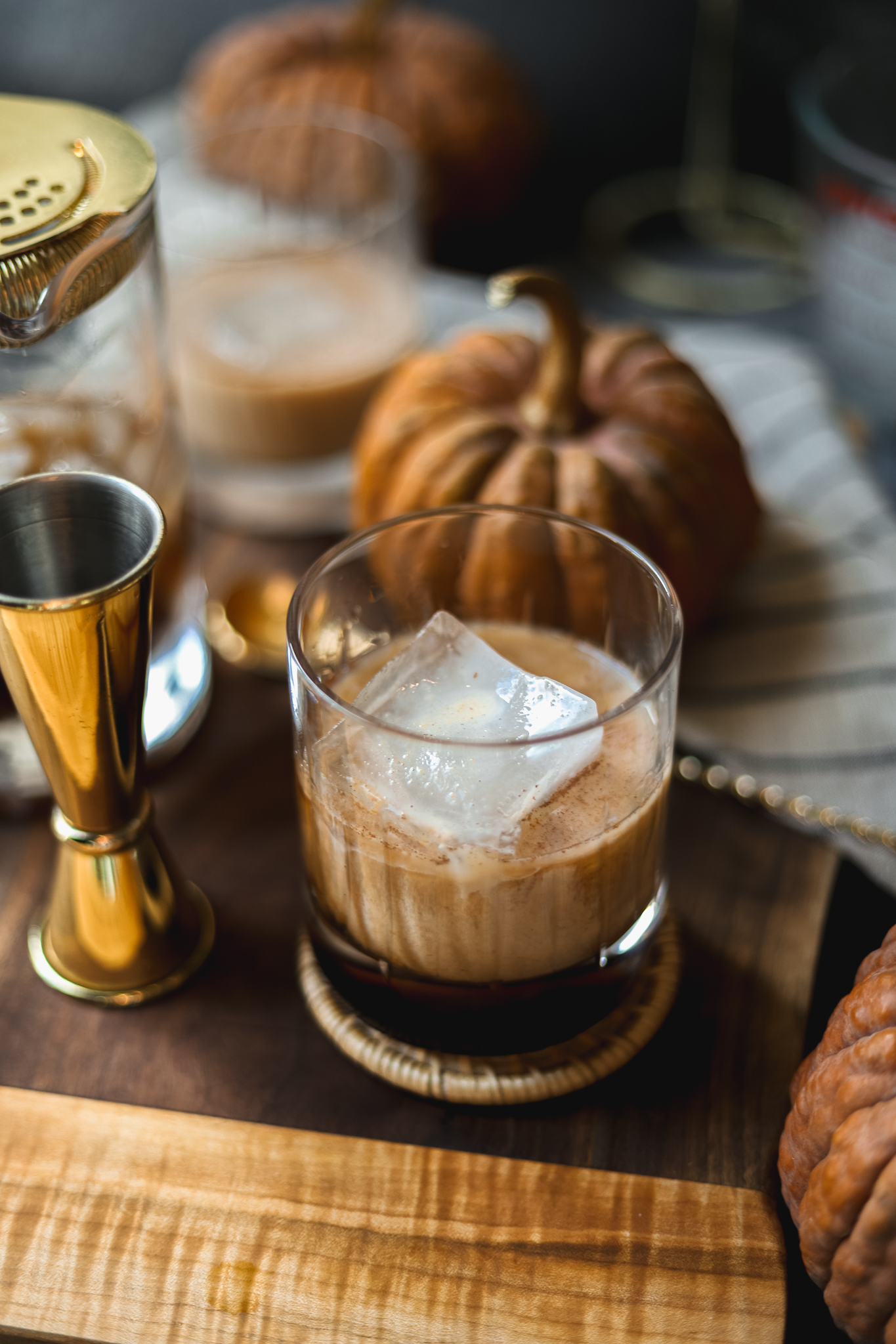 A picture of two pumpkin pie white russians surrounded by pumpkins and drinkware. 
