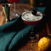 Two amaretto sours on a cutting board with cherry garnish