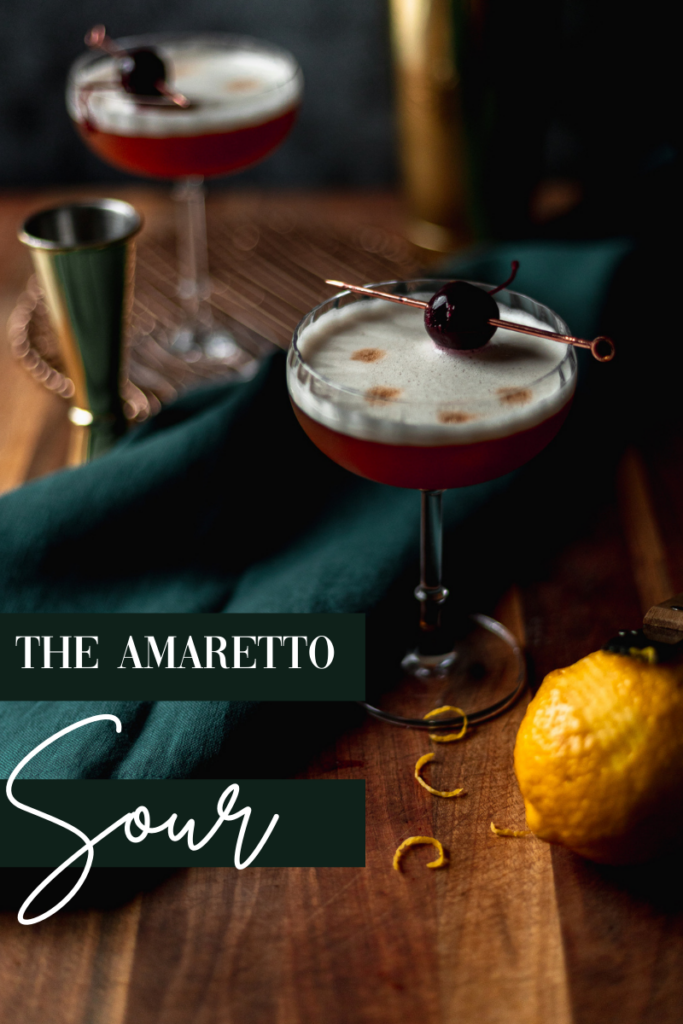 A photo of two amaretto sours on a wooden cutting board with brandied cherries