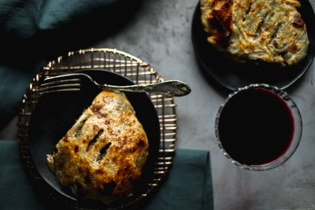 An overhead shot of two individual beef wellingtons with red wine