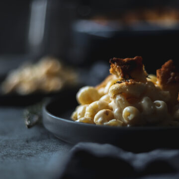 A plate of smoked gouda mac and cheese with a glass of read wine and thyme