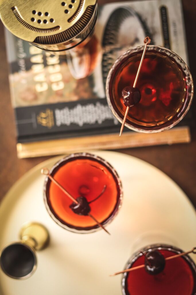 Three Manhattan cocktails, all garnished with cocktail cherries.