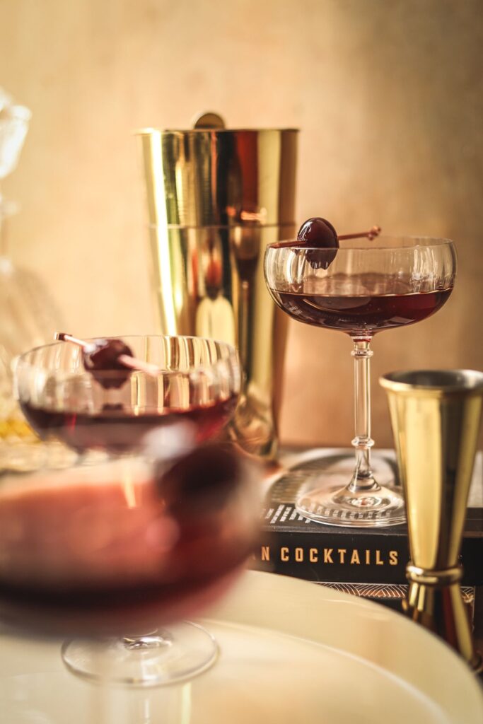 Three Manhattan cocktails, with gold barware surrounding them. 