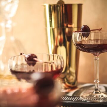 Three classic manhattan cocktails sitting by a window .