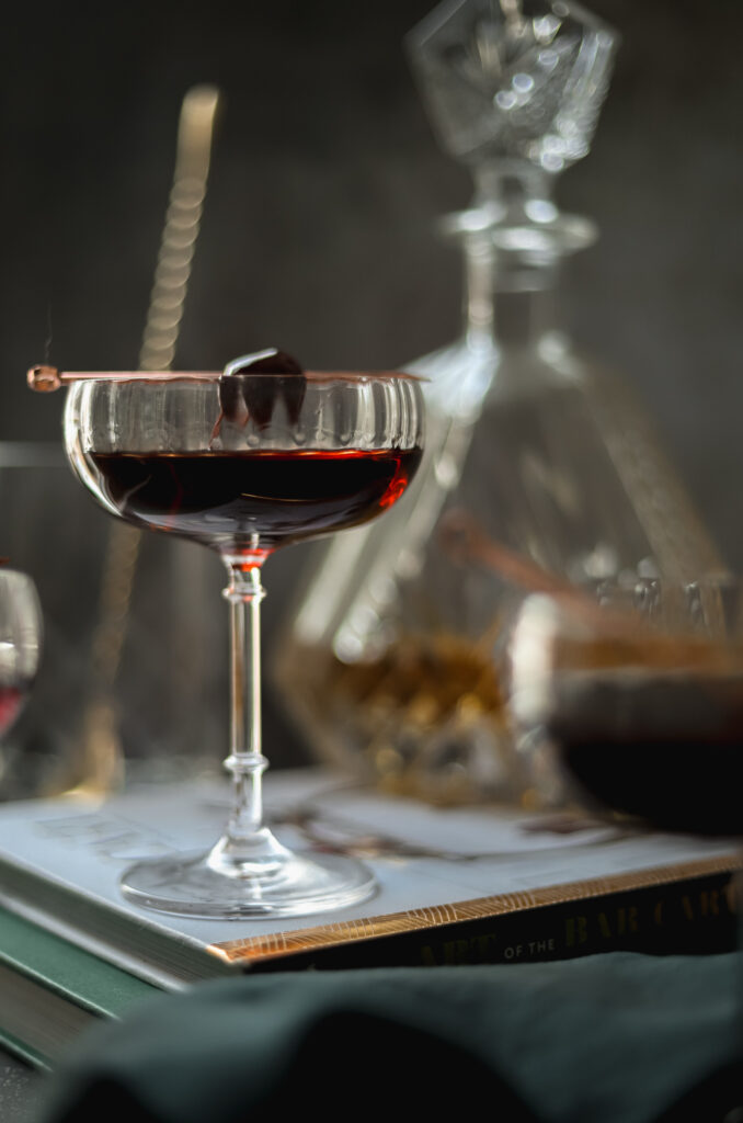 A photo of a classic manhattan cocktail with barware in the background