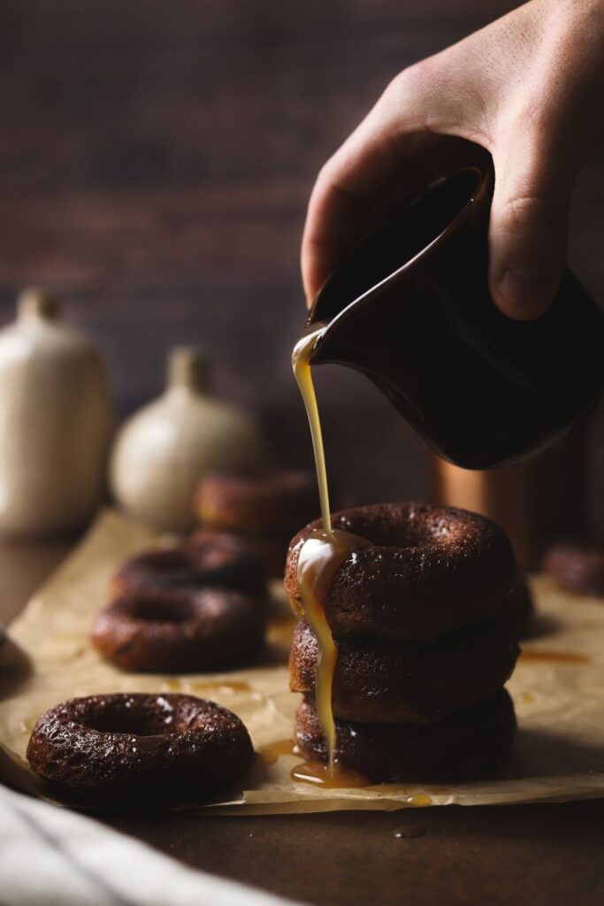 A photo of three sticky toffee doughnuts with sauce being poured on them