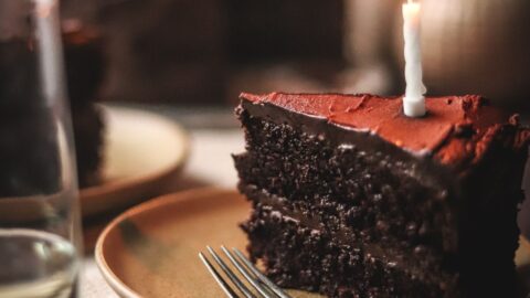 A picture of the best moist chocolate cake with candles and a fork