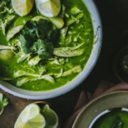 A photo of cilantro chicken soup garnished with limes