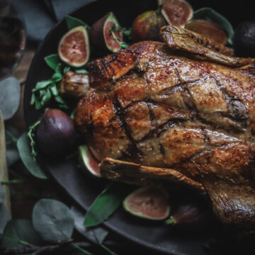 Photo of a whole roasted duck with figs and sage