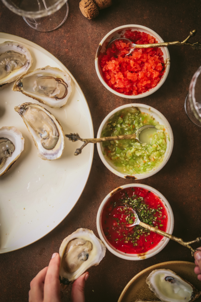 A photo of fresh oysters on the half shell and three different mignonettes