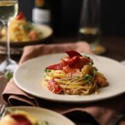 A photo of lobster pasta surrounded by glasses of champagne