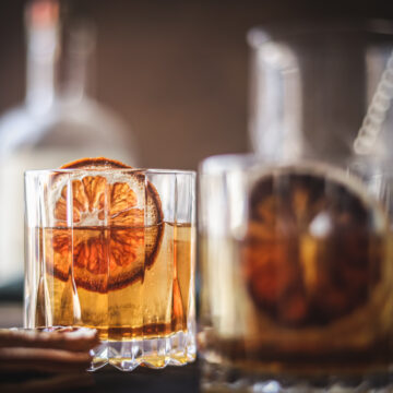 a photo of two maple old fashioned cocktails with dried oranges
