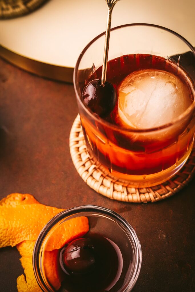 A maple old fashioned in a rocks glass with a bourbon cherry.