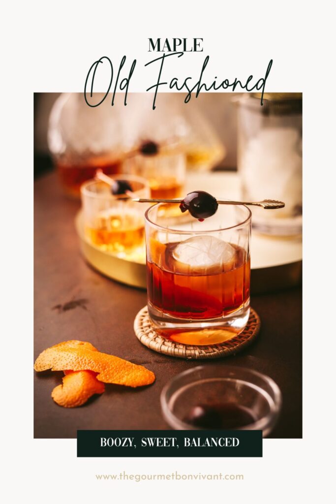 A maple old fashioned with cherries and orange peel on a white background with title text.