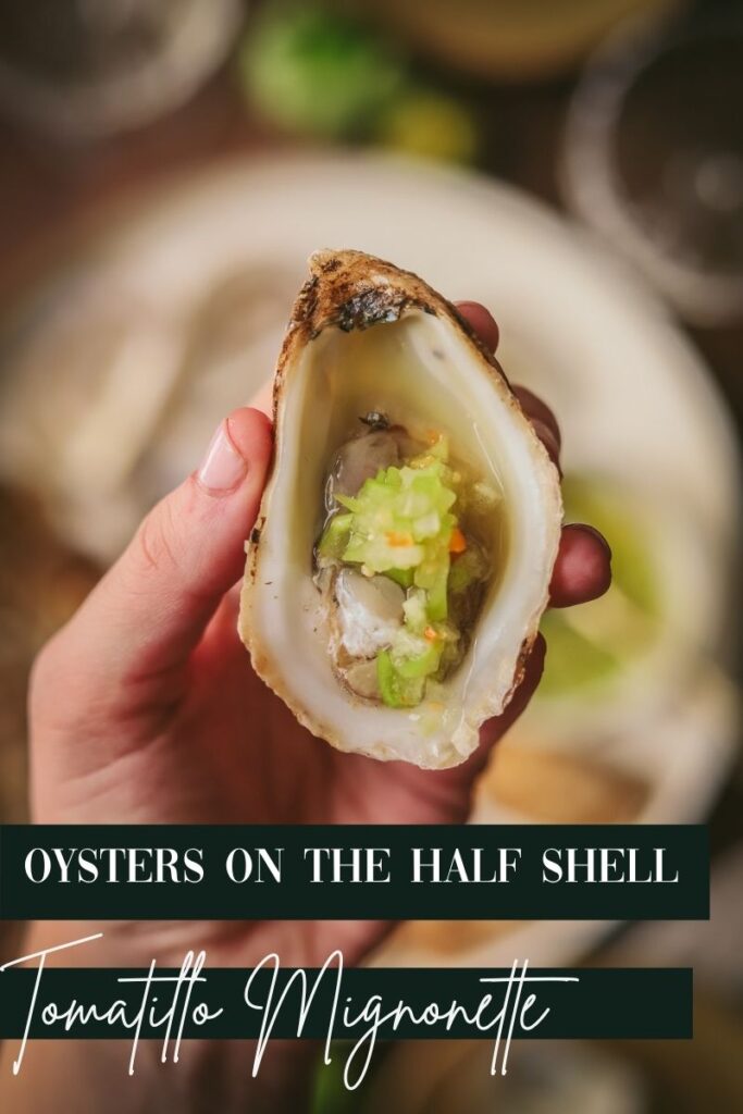 A photo of someone holding an oyster with tomatillo habanero mignonett