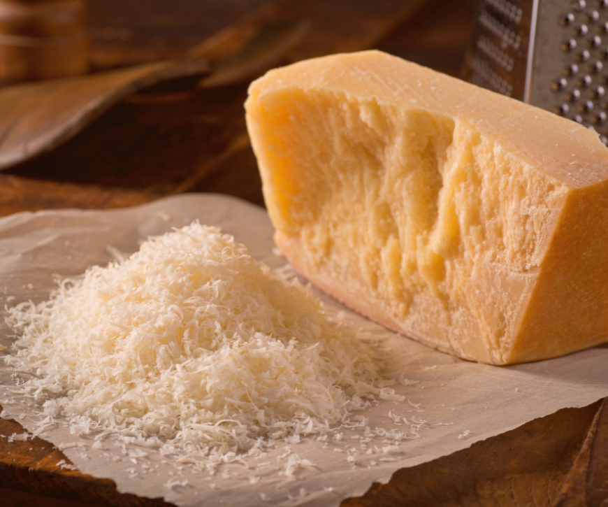 Shredded parmesan cheese beside a block of parmesan cheese