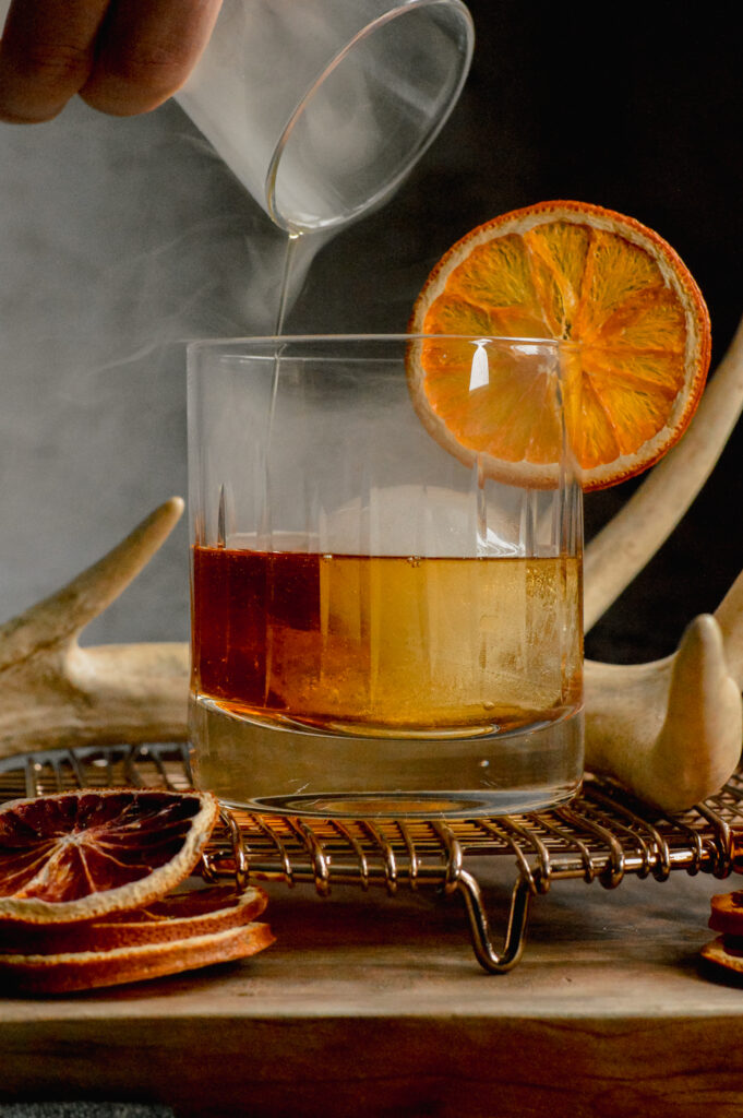 a smoked maple old fashioned being poured 