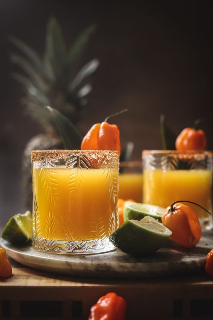 A photo of three spicy pineapple margaritas with habanero peppers