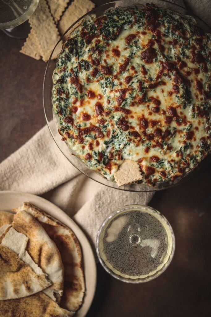 A photo of crab spinach dip with pitas and white wine