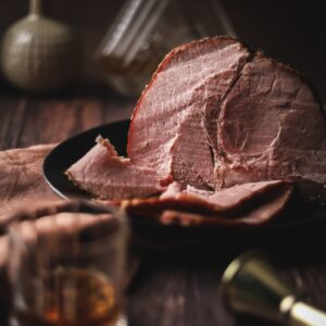 Sliced maple glazed ham with a glass of bourbon