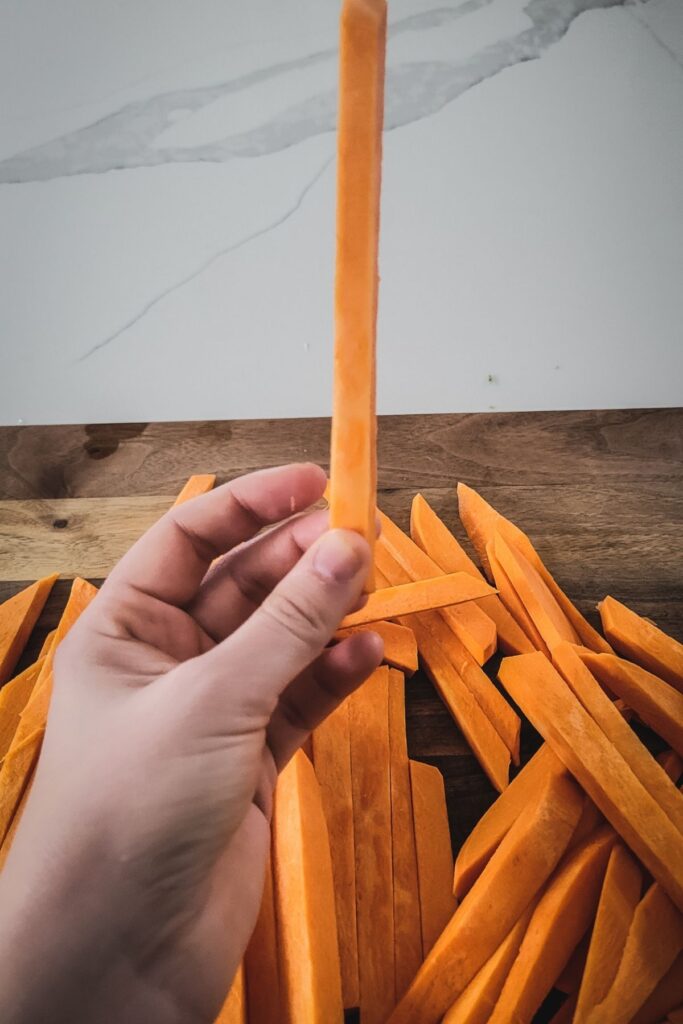 A photo of raw sweet potato fries, cut thinly.