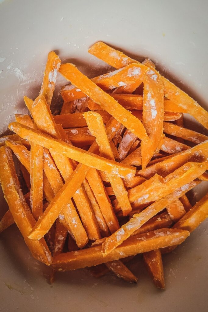 sweet potato fries in a bowl coated in olive oil and cornstarch