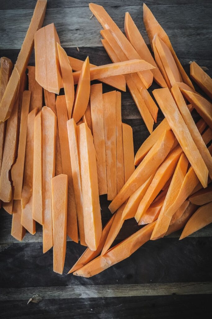 A photo of raw sweet potato fries, cut thinly.