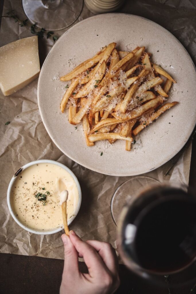 A photo of truffle parmesan fries with truffle aioli and red wine