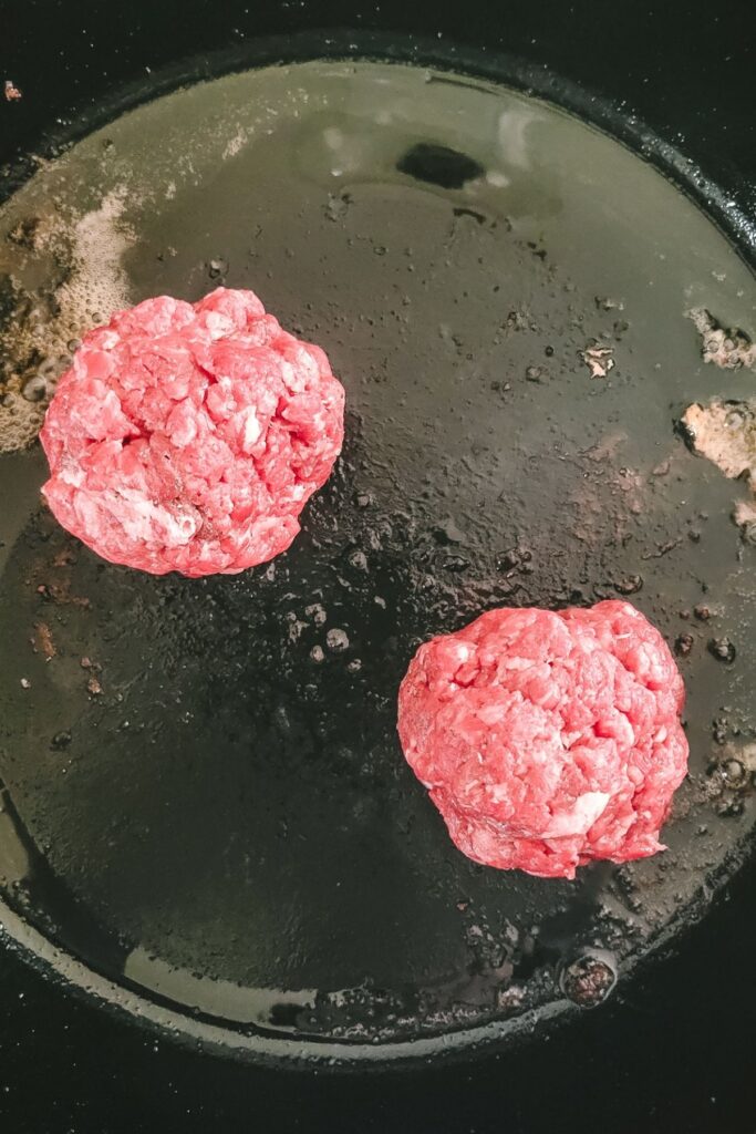 Two round patties in a cast iron skillet