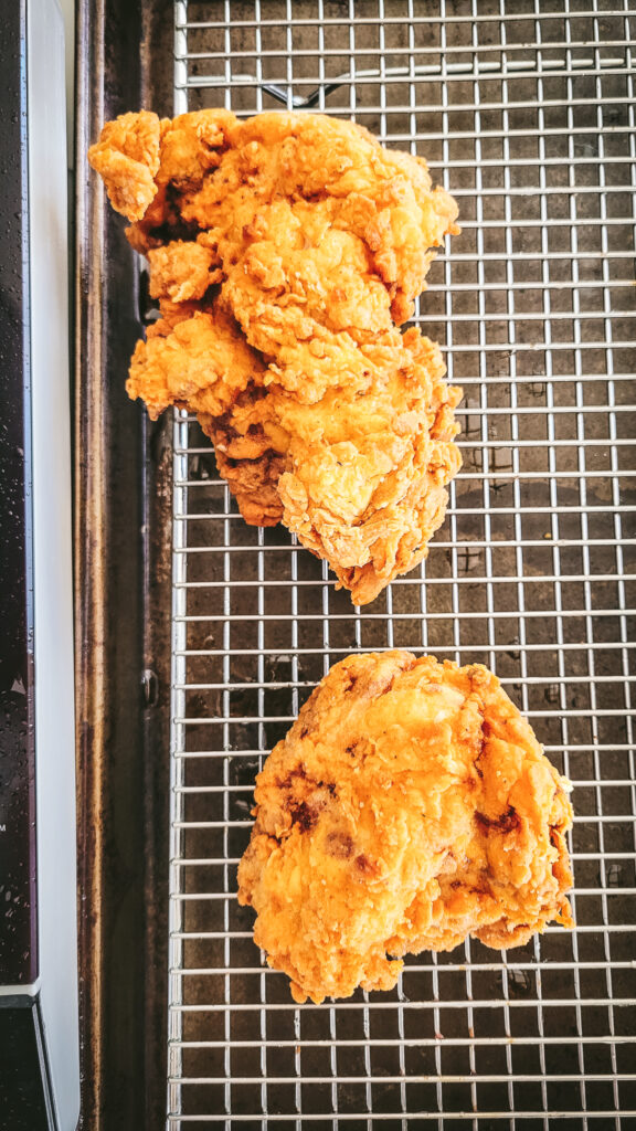 The fried chicken thighs resting on a wire baking rack