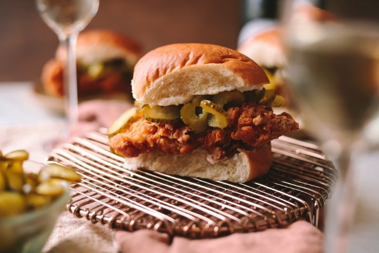 A crispy buttermilk chicken sandwich surrounded by champagne