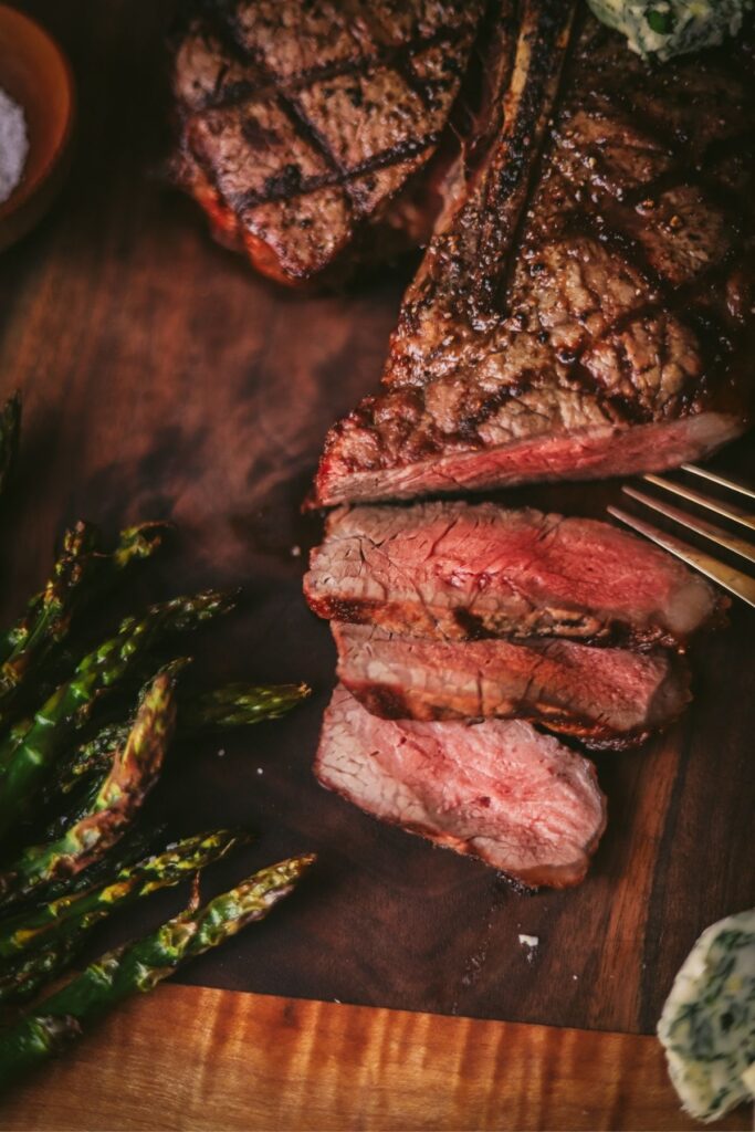 A close up of medium rare t-bone steak on the grill
