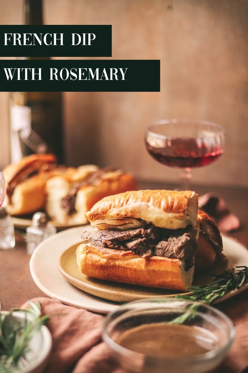 French dip sandwiches with red wine in the background.