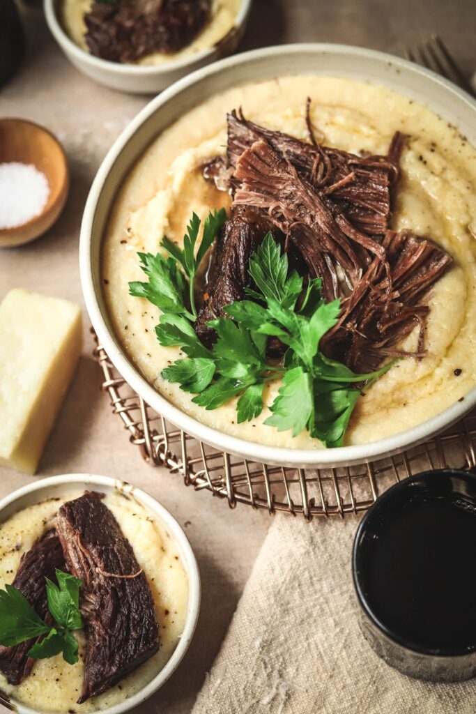 A photo of a bowl of red wine braised beef with polenta