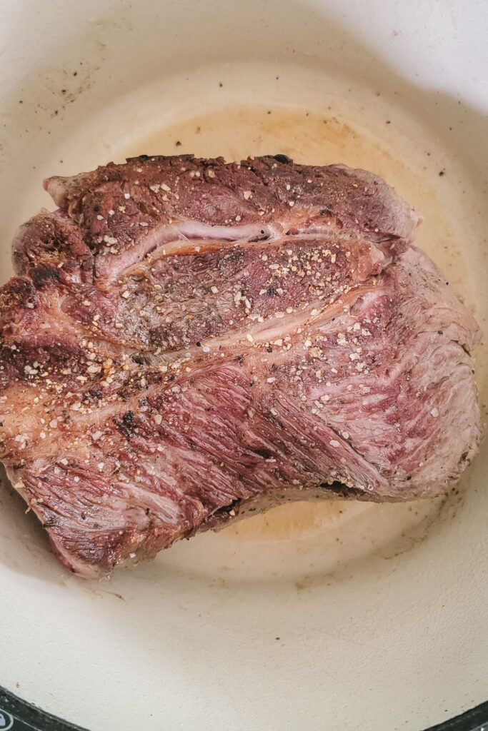 Searing the chuck roast on all sides in a Dutch oven