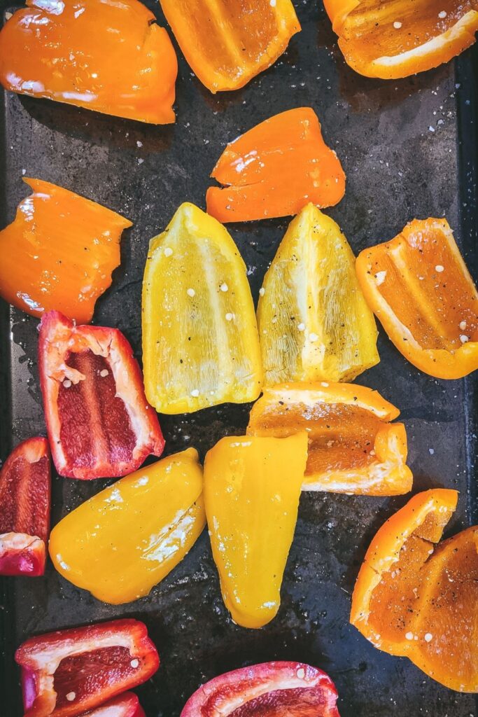 bell peppers mixed with salt, pepper and olive oil on a baking tray.