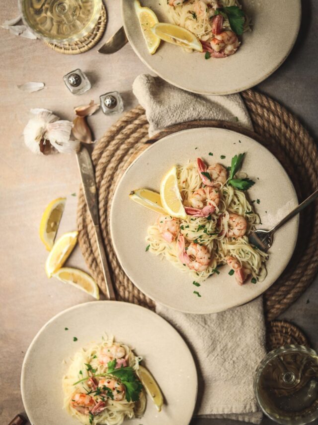 Three plates of shrimp scampi pasta.
