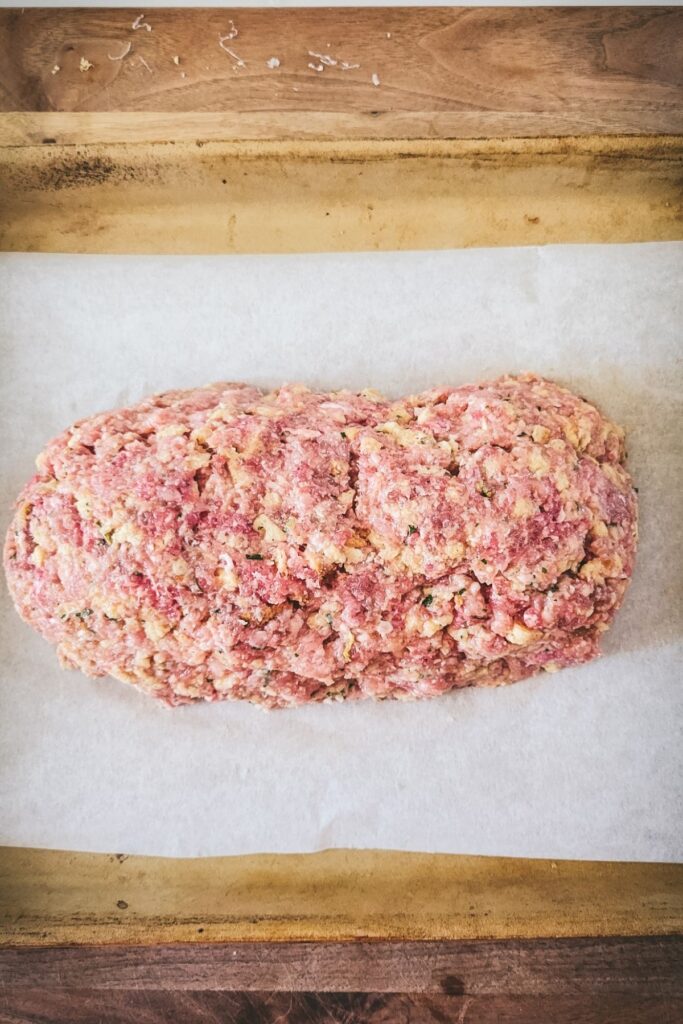 Meatloaf shaped into a loaf on baking sheet. 