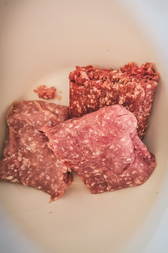 Ground beef, ground veal, and ground pork in a bowl. 