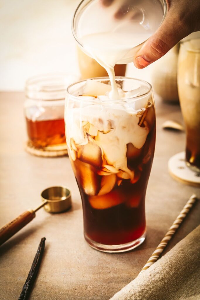 Cream being poured over a coffee with vanilla syrup. 