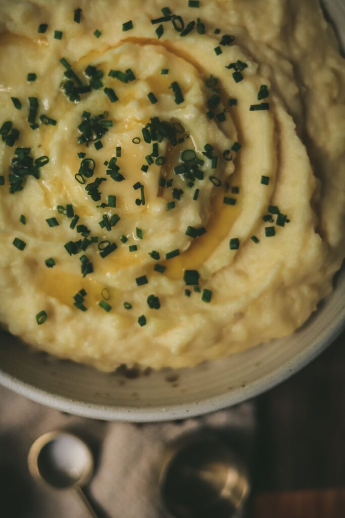 A bowl of mashed potatoes with chives and butter.