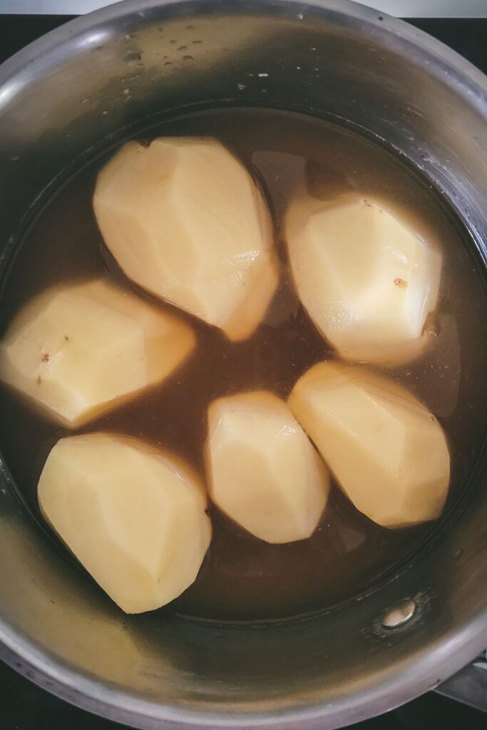 Cooked whole potatoes peeled with chicken broth