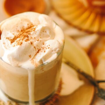 pumpkin spice latte with a spoon and whip cream overflowing.