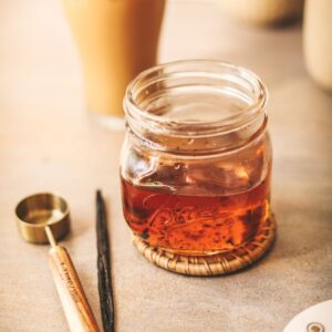 A jar of homemade syrup - iced coffee in the background.