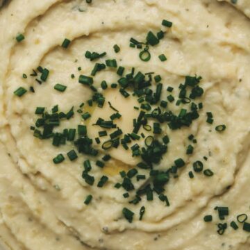 Overhead close-up shot of mashed potatoes with chives and butter.